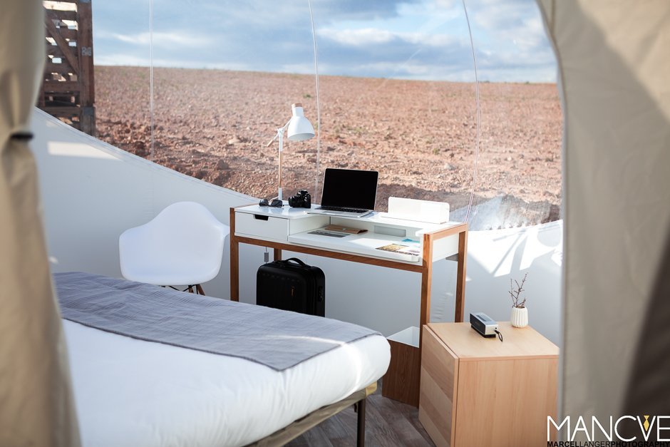 Hotel Aire de Bardenas Bubble Home Wohnzimmer Schreibtisch Bett Wüste Panorama Fenster Macbook Minimalistisch Holz weiß modern