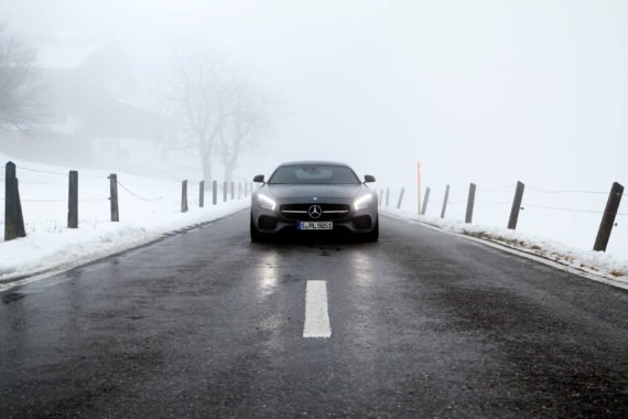 Nebel Scheinwerfer Lichtkegel Auto Grau Zaun Schnee Berge