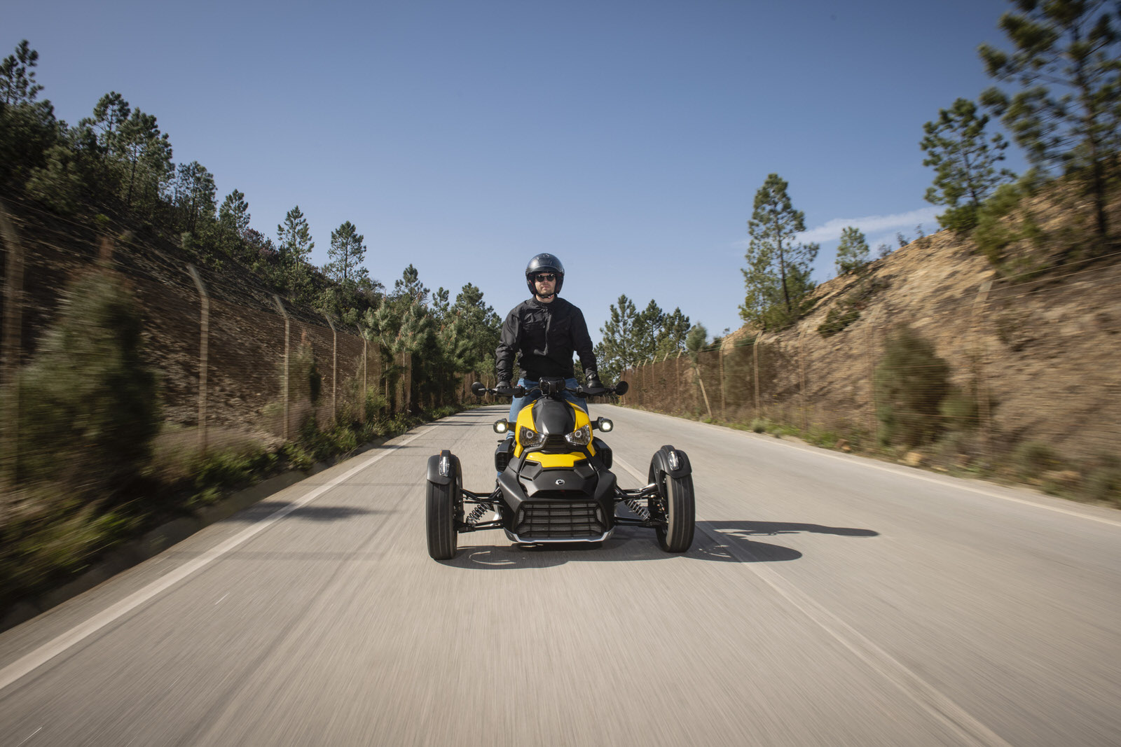 Driver standing on his three wheeler Can-Am Ryker in yellow